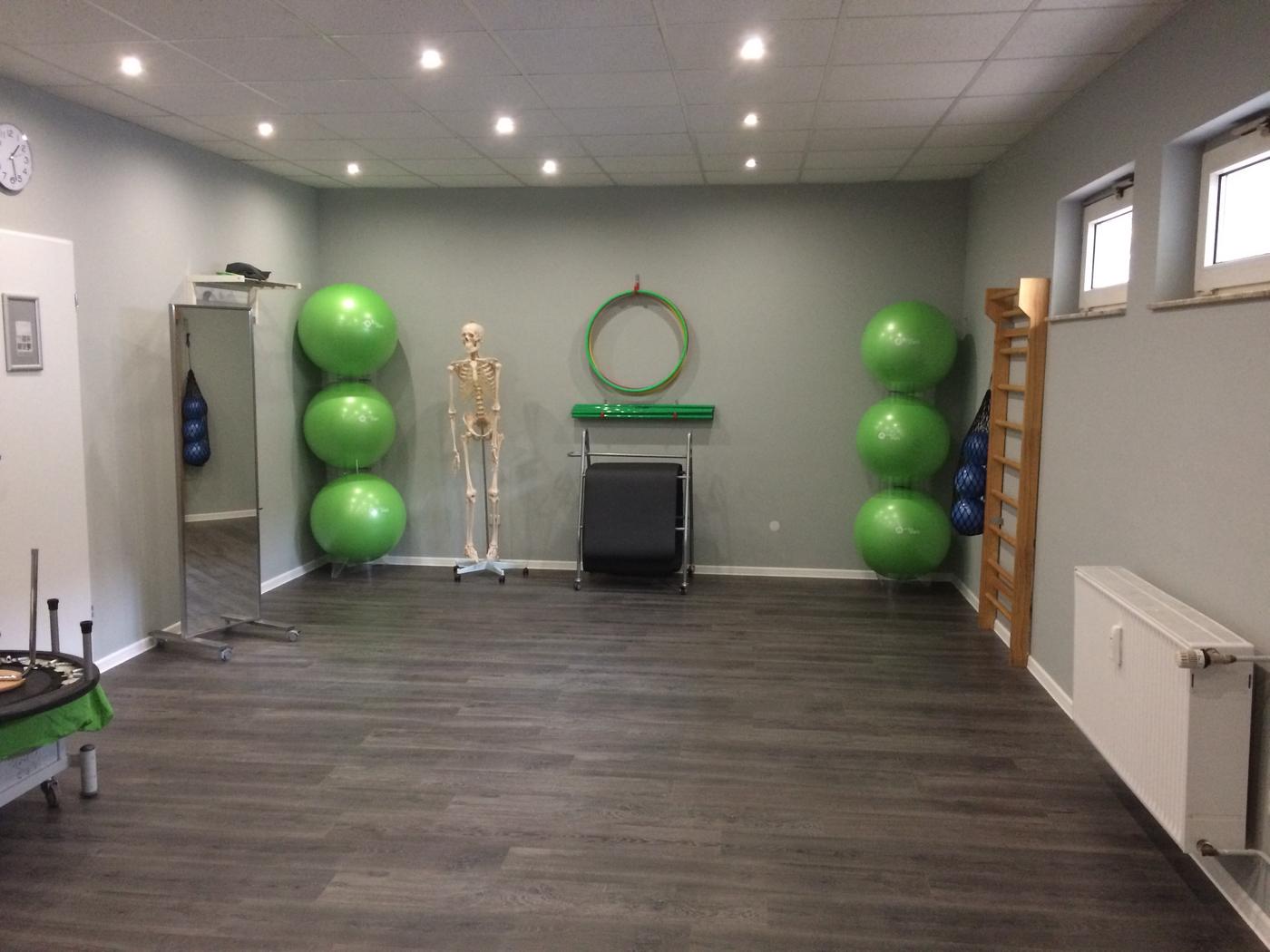 Therapieraum mit grünen Gymnastikbällen, Skelettmodell und Sprossenwand